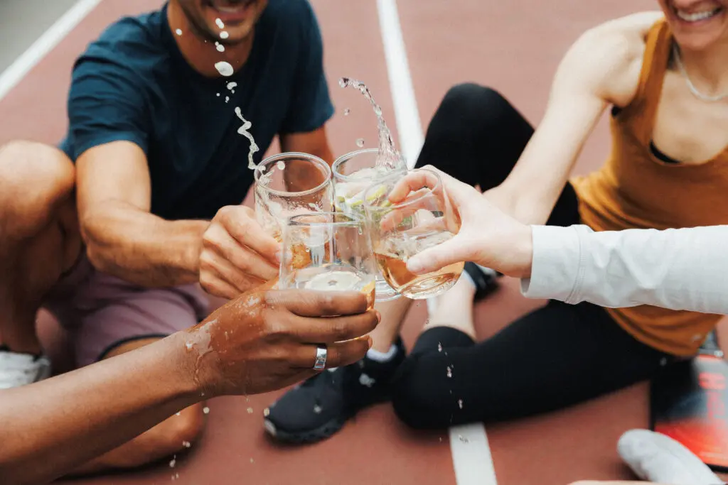 Four hands cheersing Govino shatterproof glasses on a pickleball court