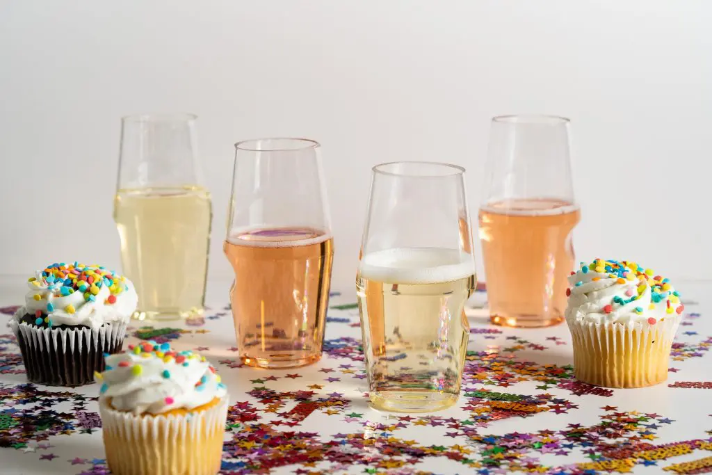 Reusable plastic champagne flutes filled with sparkling wine at a festive celebration table.